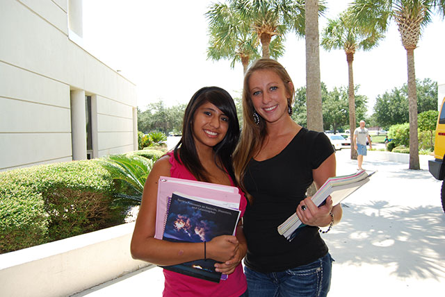 Two female student holding books.